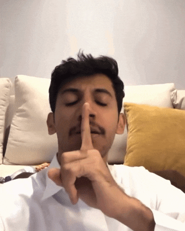 a man in a white shirt is making a shhh gesture