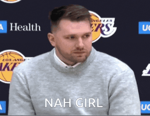 a man in a grey sweater says nah girl in front of a lakers logo