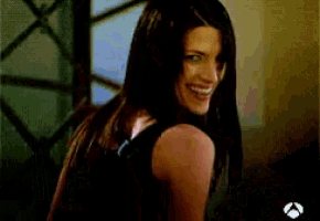 a woman in a black tank top is smiling in a blurry photo
