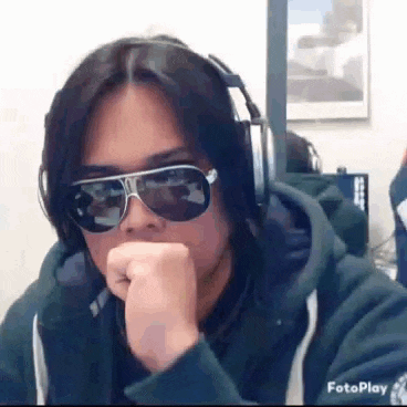a man wearing sunglasses and headphones is sitting at a desk .