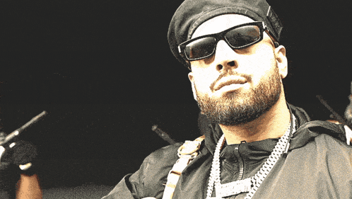a man with a beard wears sunglasses and a black hat