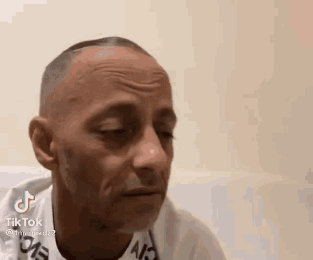 a bald man is sitting on a couch with his eyes closed and making a funny face .