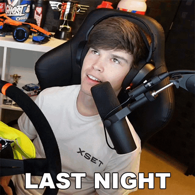 a man wearing headphones and a shirt that says xset is sitting in front of a microphone that says last night