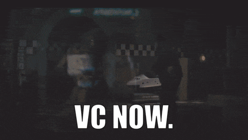a man standing in a dark room with the words vc now