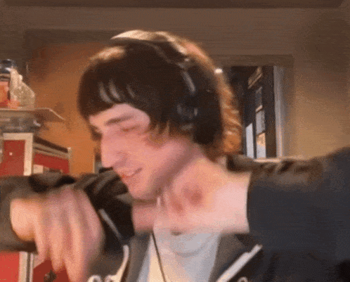 a man wearing headphones and a black jacket is smiling