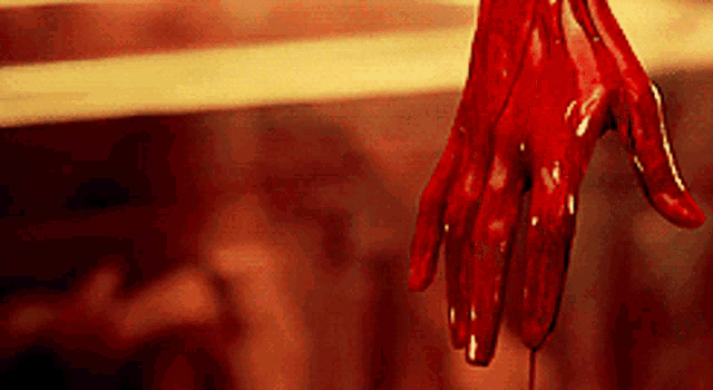 a close up of a bloody hand with a drop of blood coming out of it
