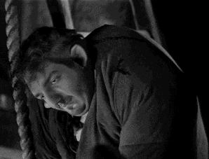 a man is hanging from a rope and looking down .