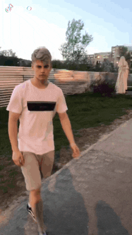 a man in a white t-shirt walking down a sidewalk