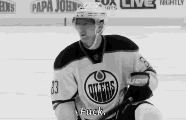 a hockey player wearing a jersey that says oilers is sitting on the ice .