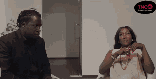 a man and a woman are sitting next to each other with a tnc logo in the background