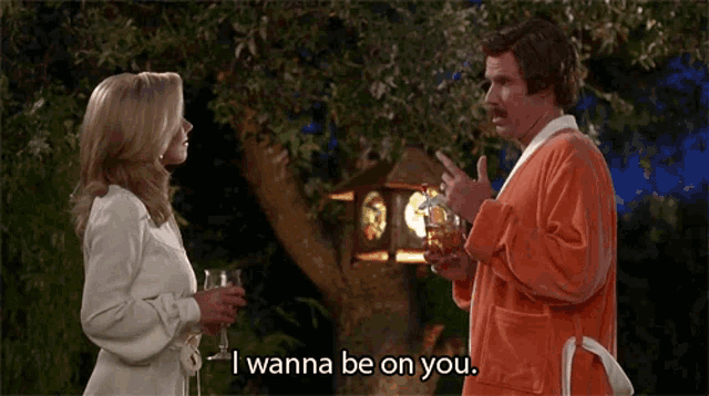 a man in an orange robe is talking to a woman who is holding a glass of wine and saying i wanna be on you
