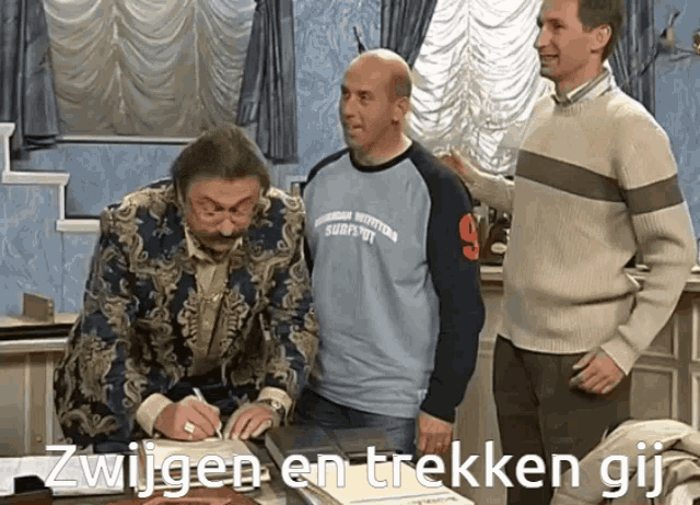 a man wearing a shirt that says zwijnen en trekken gij is signing a document