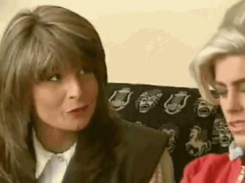 a woman in a suit and tie is sitting next to another woman in a red shirt .