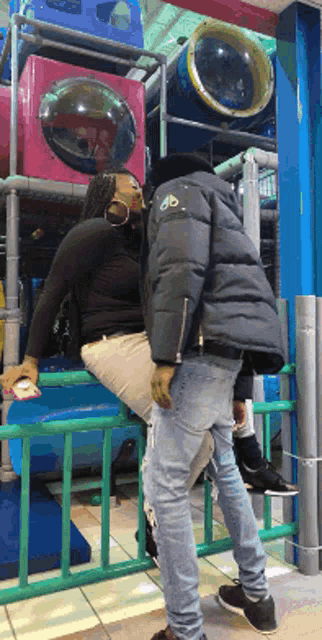 a man and woman kissing in a playground with a man wearing a jacket with the letter m on it