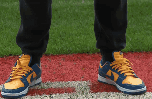 a person wearing blue and yellow nike shoes stands on a field
