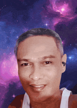 a man is smiling in front of a purple and blue galaxy