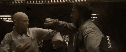 two men are standing next to each other in a dark room holding hands .