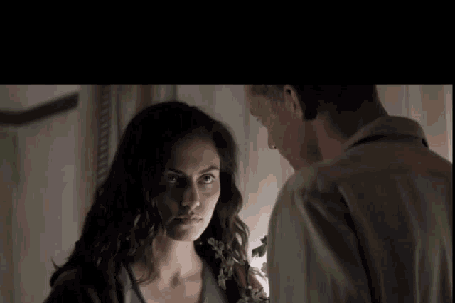 a man and a woman are looking at each other in a room