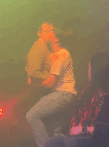 a man in a white t-shirt is dancing in a dark room