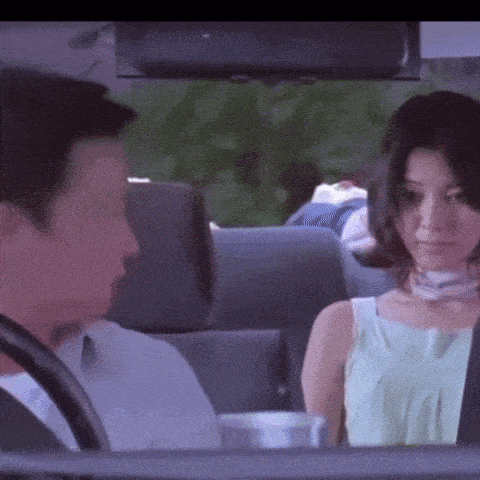 a man and woman are sitting in a car looking at each other