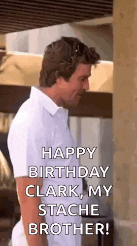 a man in a white shirt is standing next to a wall and says happy birthday clark , my stache brother .