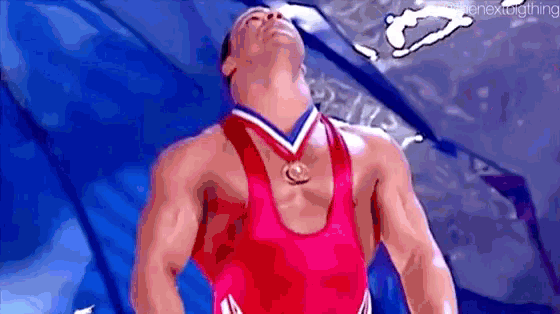 a wrestler wearing a medal around his neck is looking up .