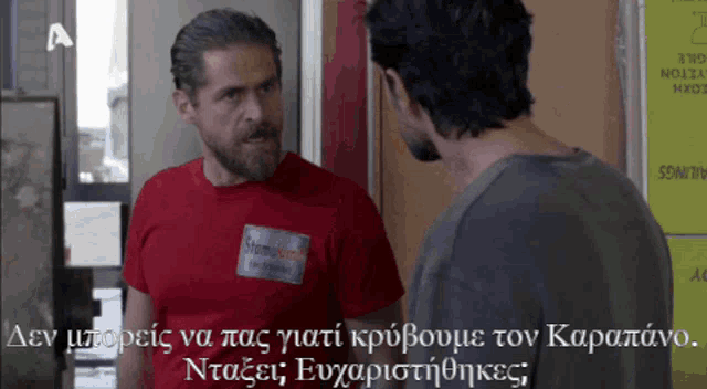 a man wearing a red shirt with a name tag that says stefanos talks to another man