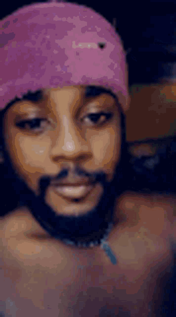 a man with a beard is wearing a pink hat and smiling .
