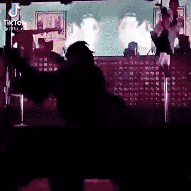 a silhouette of a person dancing on a stage with a tik tok logo in the background