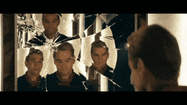 a man looks at himself in a broken mirror
