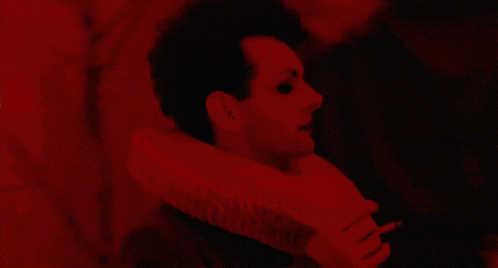 a red background with a person in a white collar holding a fan