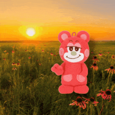a red teddy bear stands in a field of flowers at sunset