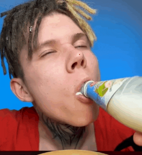 a young man with dreadlocks is drinking from a bottle with a label that says ' yogurt ' on it