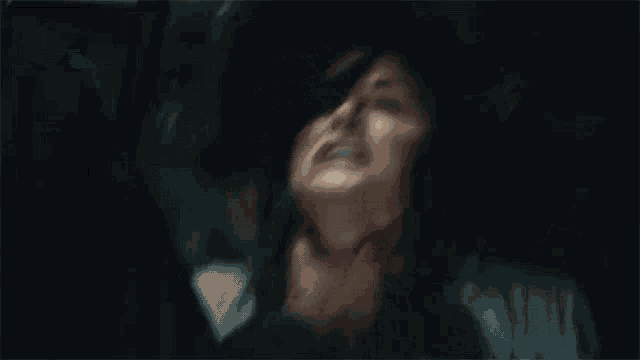 a man is holding a woman 's neck in a car in a dark room .
