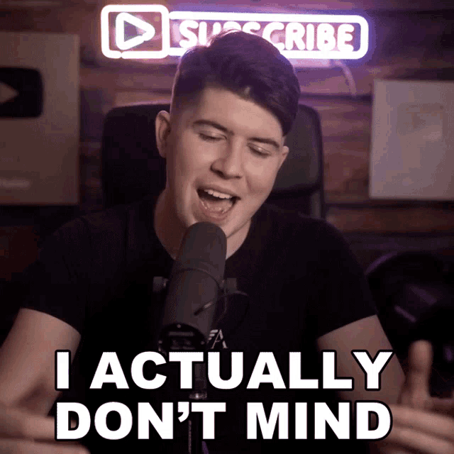 a man singing into a microphone with the words i actually do n't mind behind him