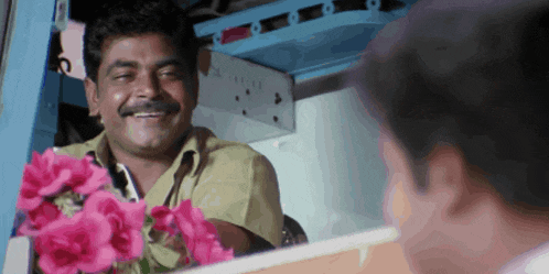 a man with a mustache is smiling while holding flowers