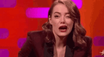 a woman in a suit is making a funny face while sitting in front of a red background .