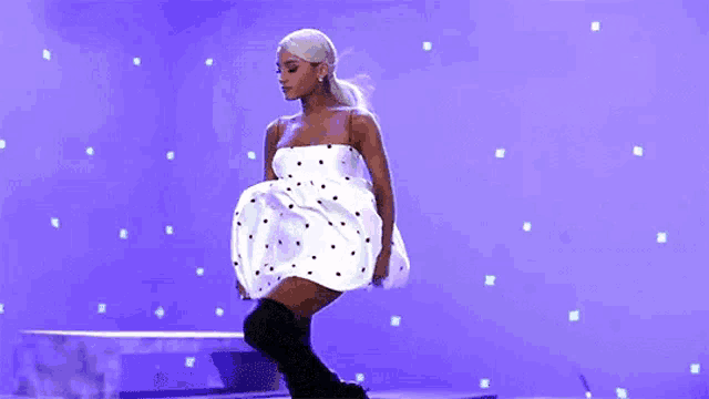 ariana grande is wearing a white polka dot dress and over the knee boots .