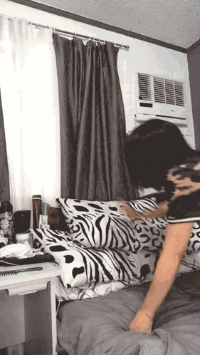 a woman is laying on a bed with a zebra print comforter