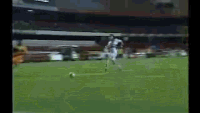a soccer game is being played in a stadium and a player is kicking the ball