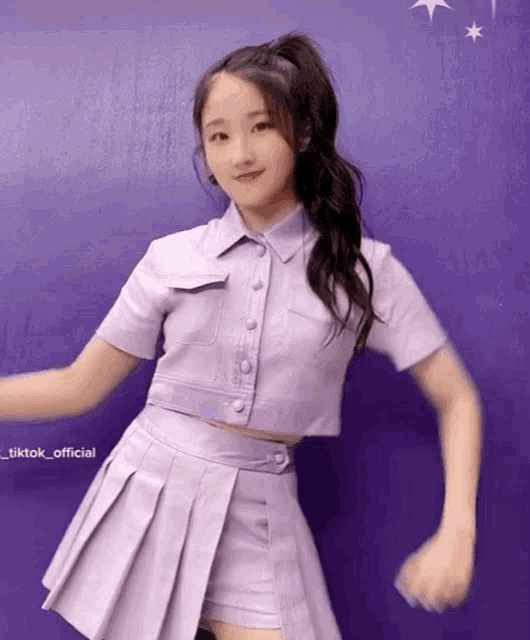 a girl in a purple outfit is dancing in front of a purple background