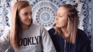 two women are looking at each other and one of them is wearing a sweater that says ' brooklyn ' on it