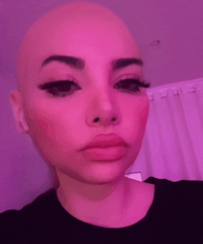 a close up of a woman 's face with a bald head and long eyelashes .