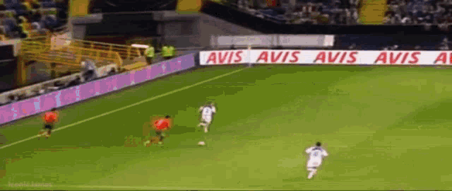 a soccer game is being played on a field that has avis advertisements on the sidelines