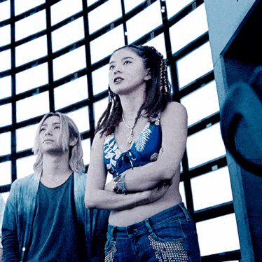 a man and a woman standing next to each other with their arms crossed and looking up