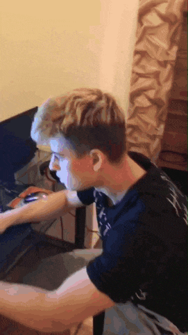 a young man is sitting at a desk playing a video game with a mouse