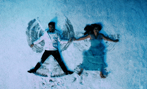 a man and a woman are laying in the snow with wings drawn in the snow