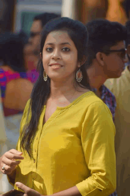 a woman in a yellow shirt stands in a crowd of people