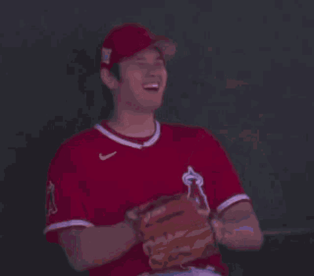 two baseball players are sitting in a dugout and one of them is wearing a red nike jersey