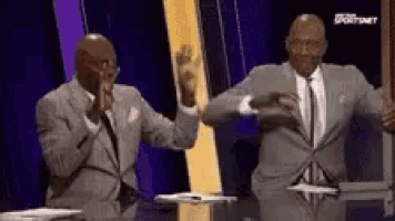 two men in suits are dancing in front of a microphone on a stage .